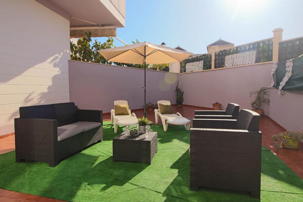 a patio with chairs and tables and an umbrella at SpainKarmaSun in Torrox Costa