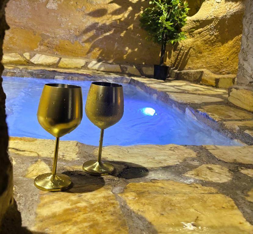 two wine glasses sitting next to a pool of water at Piedra y Luz in Buendía