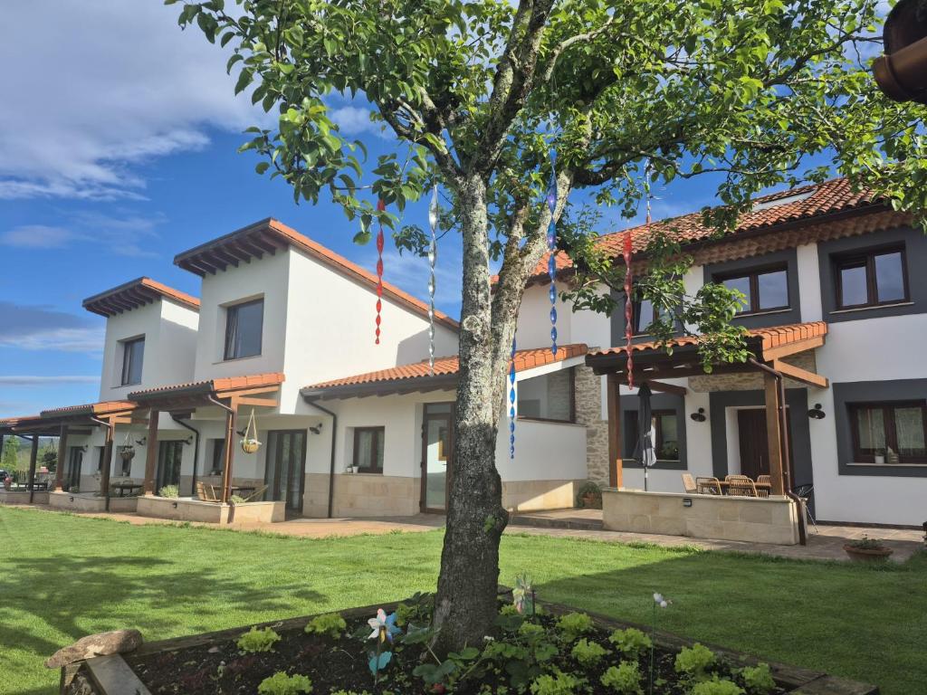 a large white house with a tree in the yard at Terradeva Apartamentos in Colombres