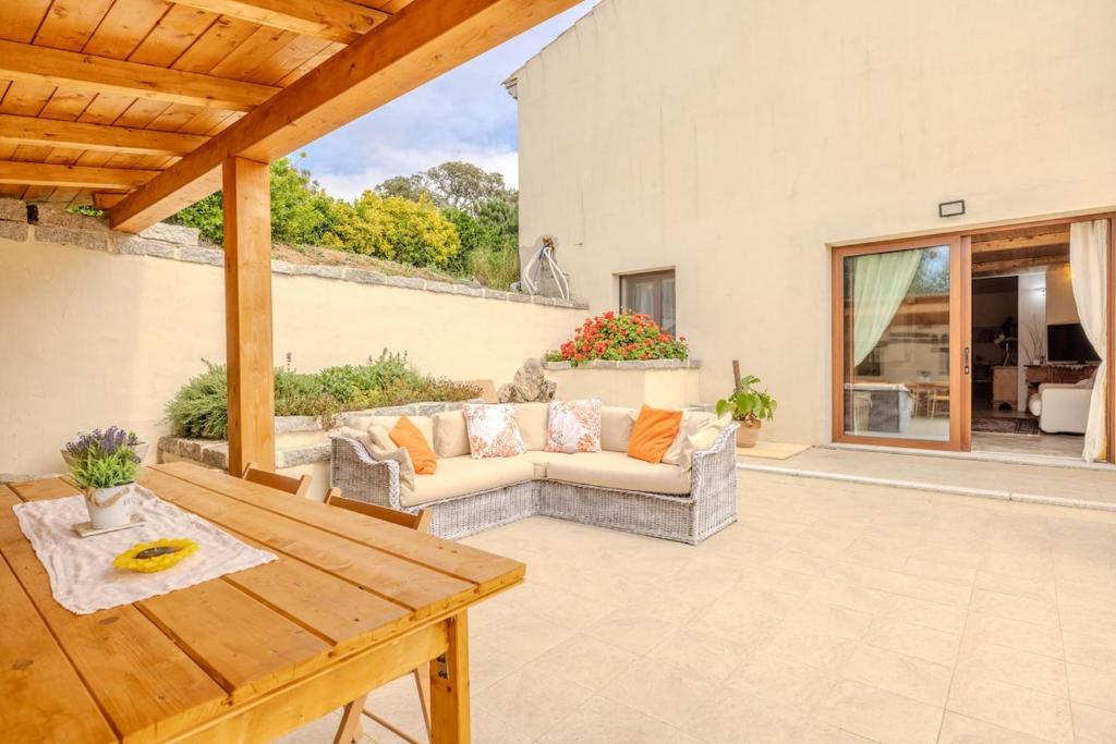 a patio with a couch and a wooden table at Villa NiLo Natura - Rustic Mountain Charm in Telti