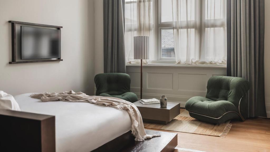 a bedroom with a bed and two chairs and a tv at Arthouse Glasgow - Newly Refurbished in Glasgow