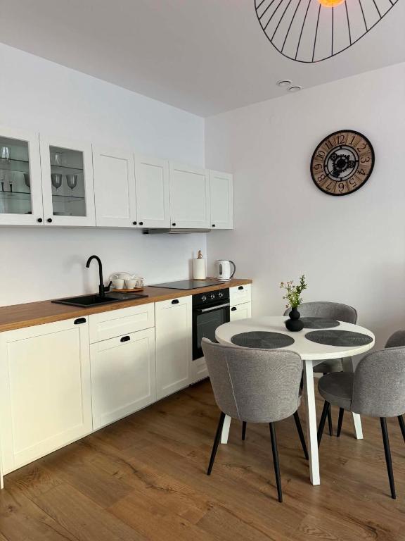a kitchen with white cabinets and a table and chairs at Apartament Bursztynowy Lębork in Lębork