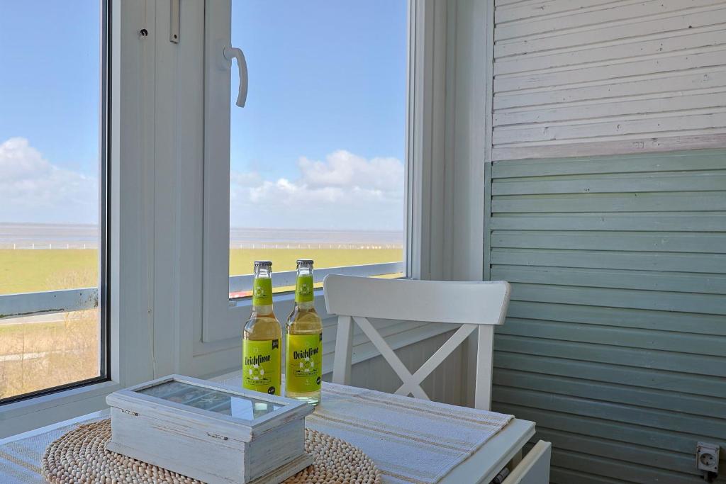 two bottles of wine sitting on a table in front of a window at Meerblick 60 in Nordstrand