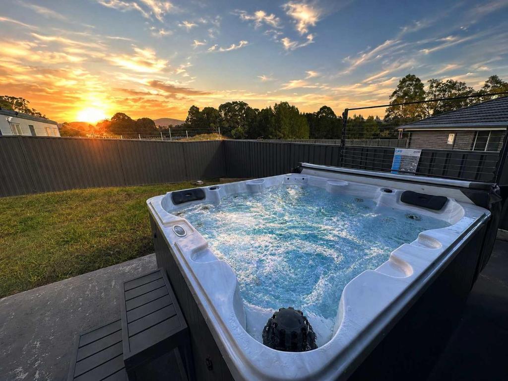 a hot tub in a yard with the sunset in the background at Hunter Hideaway in Cessnock