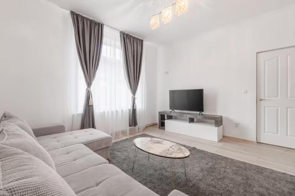 a white living room with a couch and a tv at Azure Wave - Ultra Central in Oradea