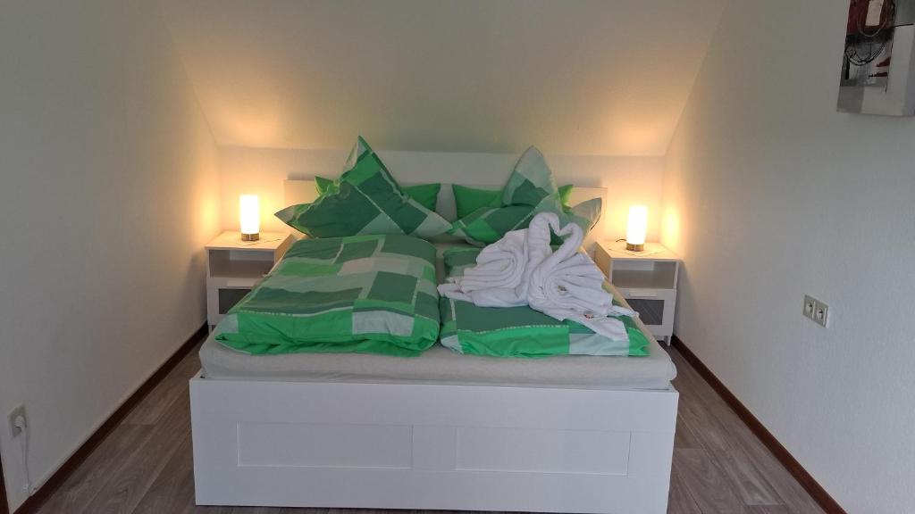 a bedroom with a bed with green pillows and two lights at Ferienwohnung Mariechen in Medebach