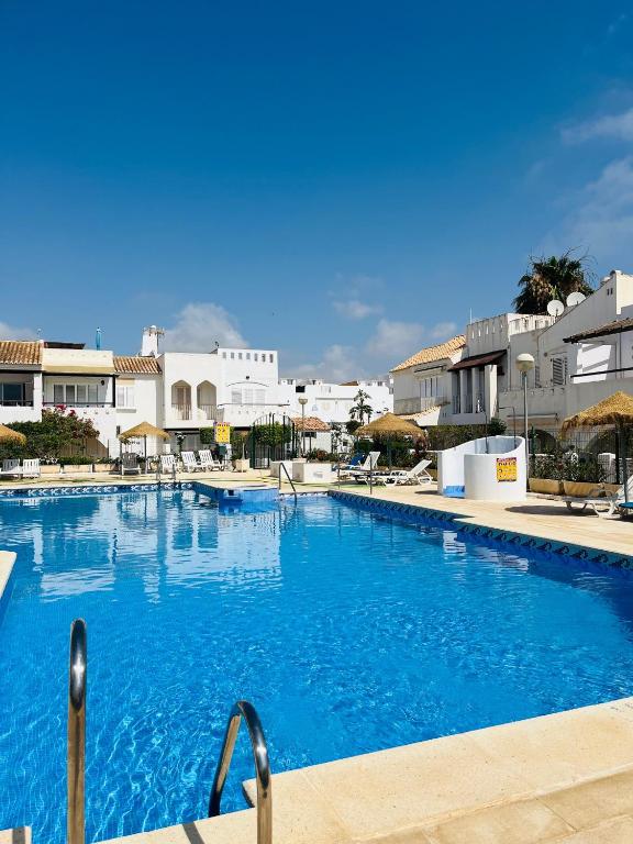 a large blue swimming pool with buildings in the background at Apartamento de las Buganvillas in Vera
