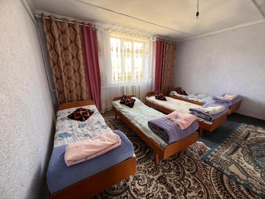 a group of three beds in a room at Temirbek Guest House in Jangy-Talap