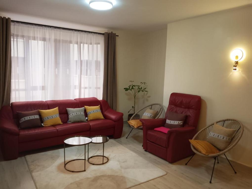 a living room with a red couch and two chairs at MAIDA Apartment - SHAWMUT SUITES in Nakuru