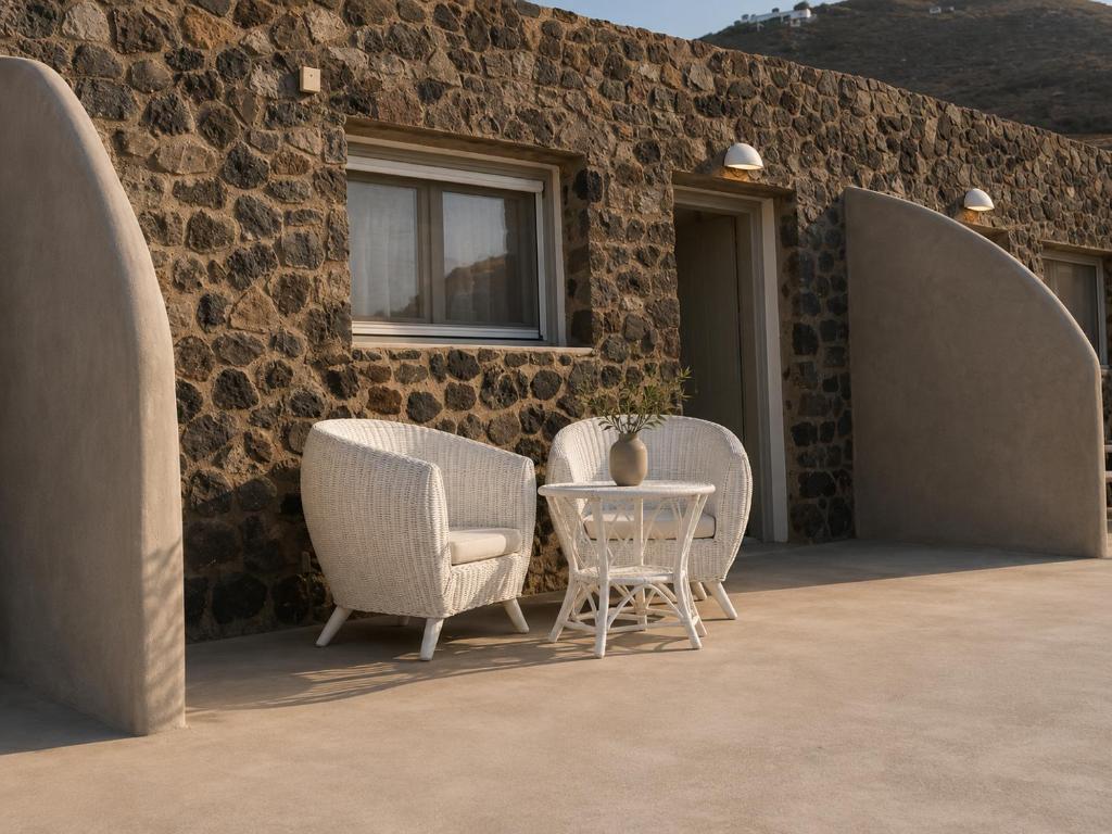 two chairs and a table in front of a building at Aenia Suites in Foinikiá