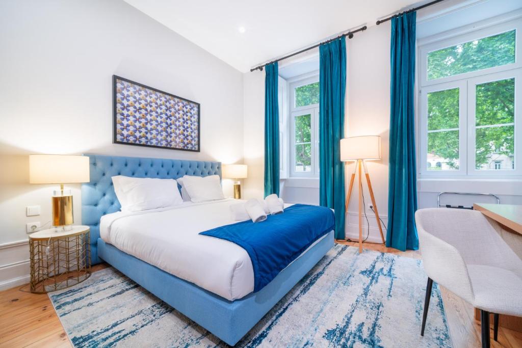 a blue and white bedroom with a bed and two windows at A&S Suítes Coimbra in Coimbra