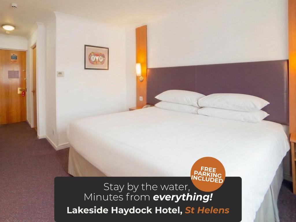 a hotel room with a large bed with a sign on it at OYO Lakeside Haydock Hotel, St Helens, A580 East Lancs, Garswood Old Road in Saint Helens