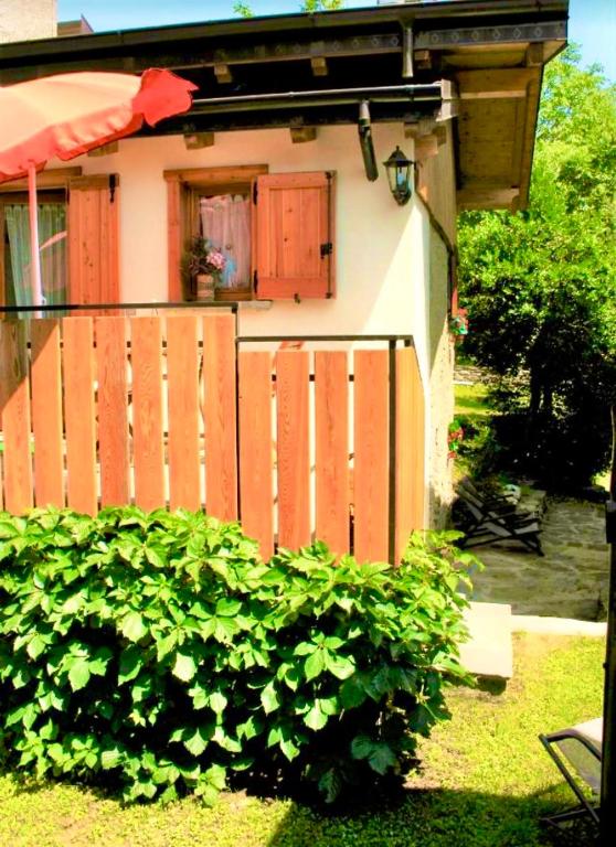 a house with a fence and a bush in front of it at Casa Bucaneve & Ciclamino in Gravedona