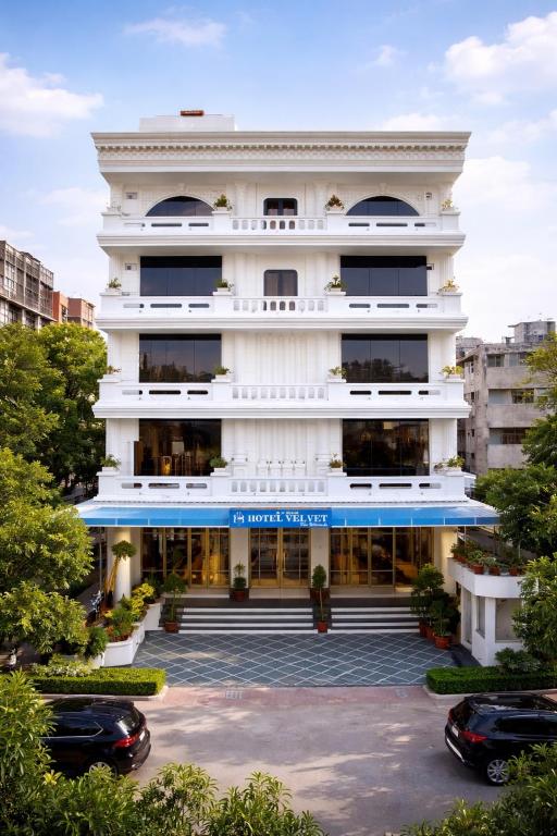 a large white building with cars parked in a parking lot at Hotel Velvet The Ultimate in Prayagraj