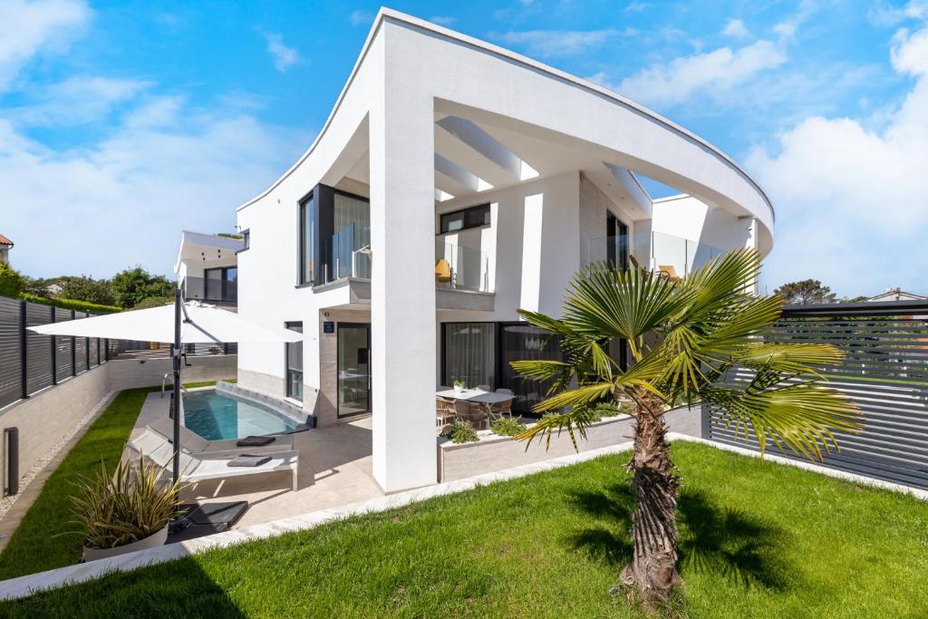 a white house with a palm tree in front of it at Villa Sarah in Vantačići