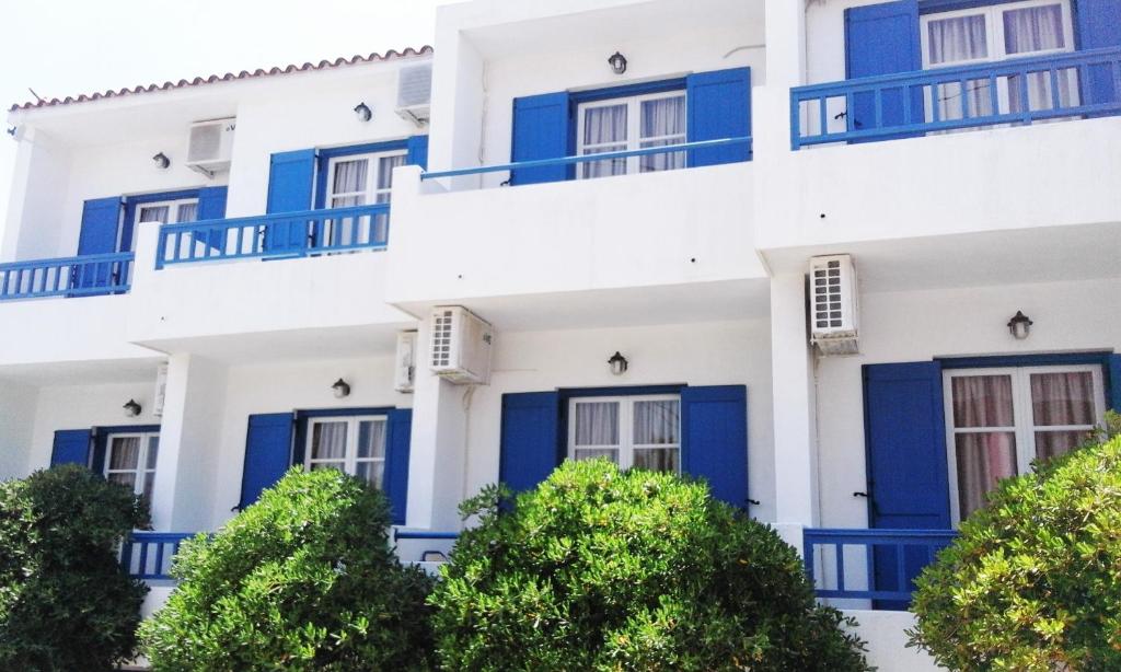 a building with blue doors and trees at Ostria Eressos Rooms in Skala Eresou