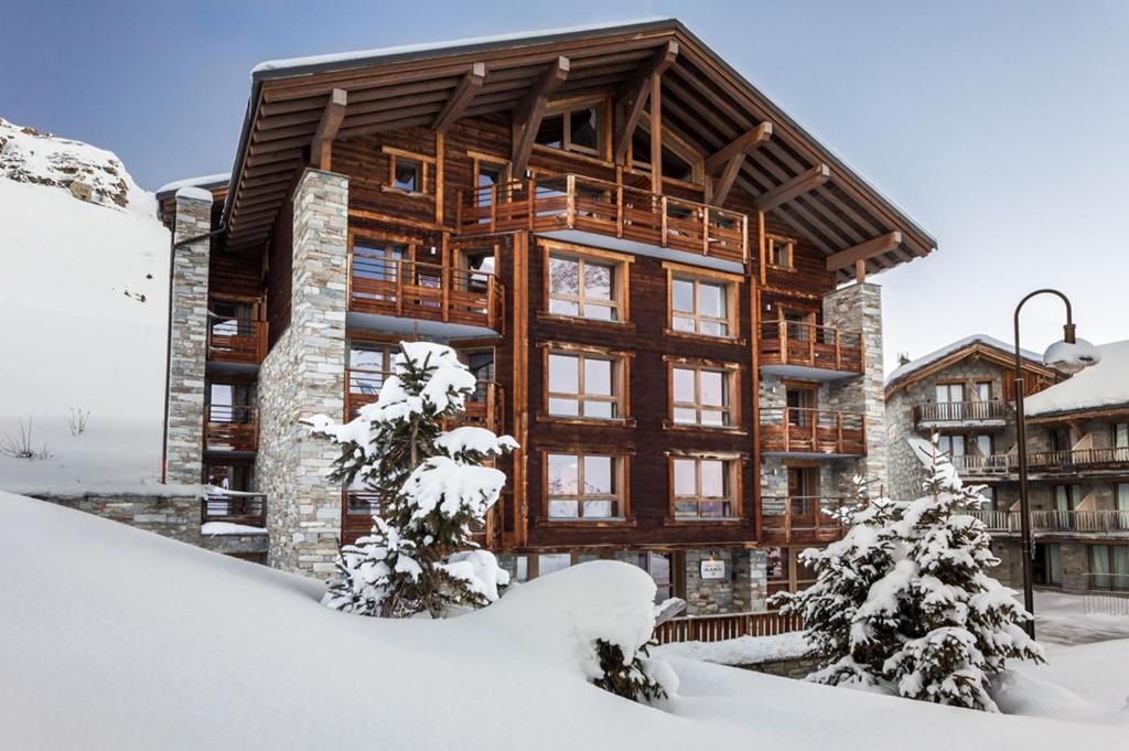 a large wooden building with snow on the ground at Résidence Almes 1 et Almes 2 by Alpapart in Tignes