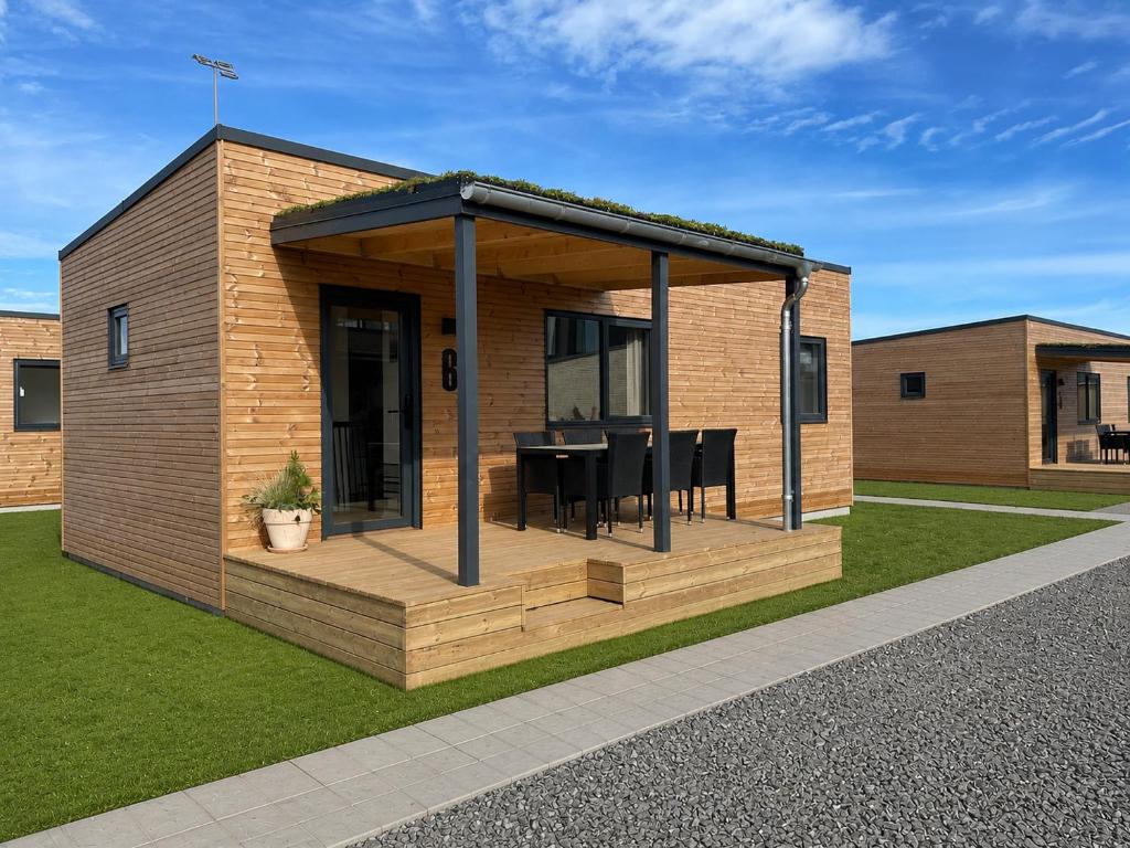 a tiny house with a deck and a table at Feriehusene Hedensted Centret - Sport, natur og velvære in Hedensted - Midtjylland