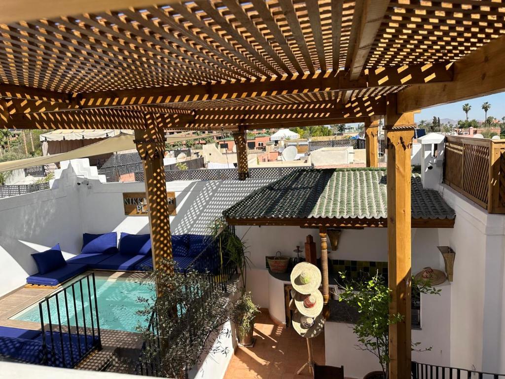 a patio with a wooden pergola and a swimming pool at Riad Le Grizzly in Marrakesh