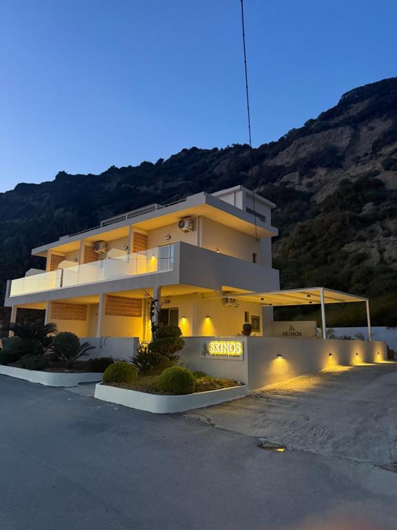 a large yellow building with lights in a parking lot at Skinos Apartments in Plakias