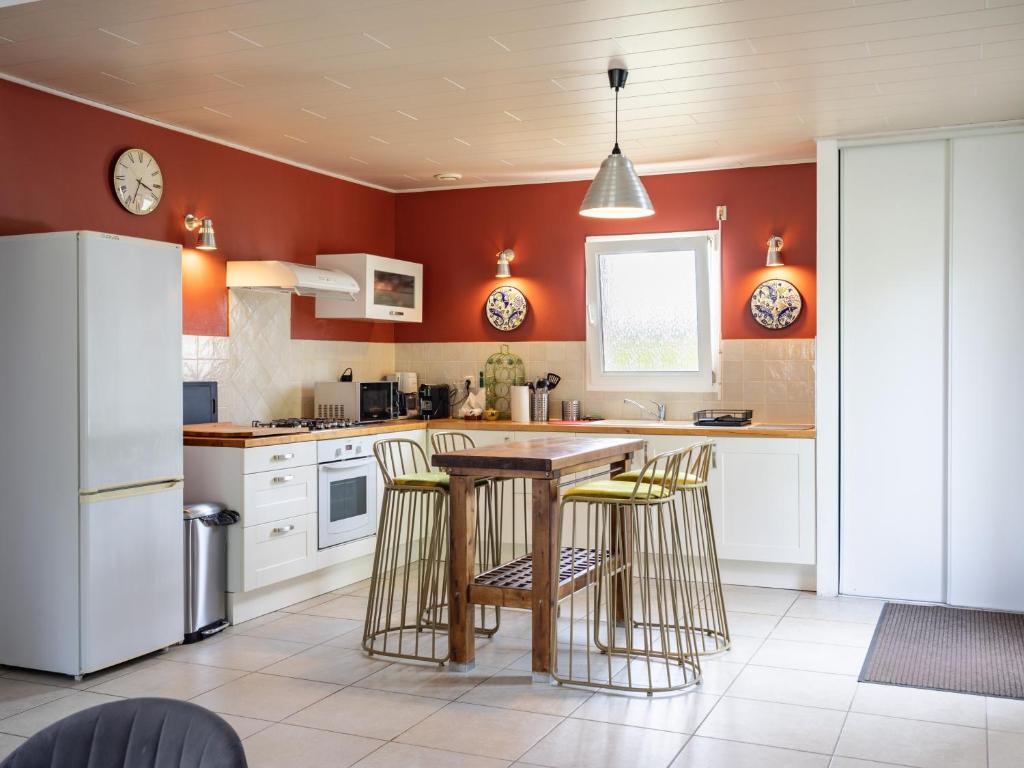 a kitchen with red walls and a wooden table and stools at War Ar Maez in Pleumeur-Bodou
