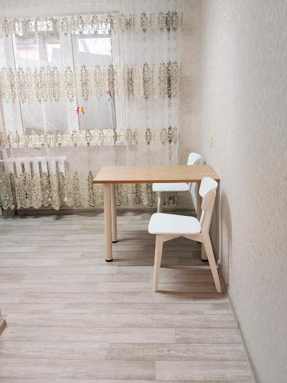a wooden table and a chair in a room with curtains at Строитель 39 in Oral