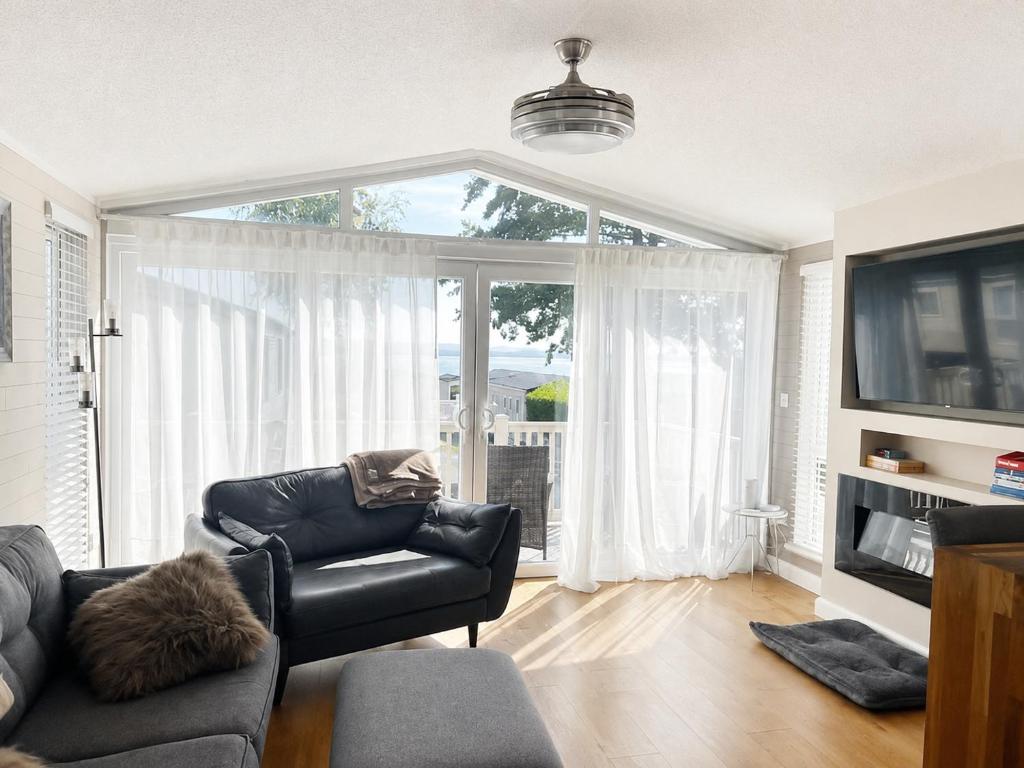 a living room with a black leather couch and a large window at 43 Harbour View in Poole