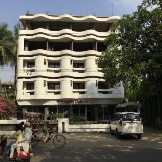 a large white building with people on bikes and a car at Atithi Palace in Bhāgalpur