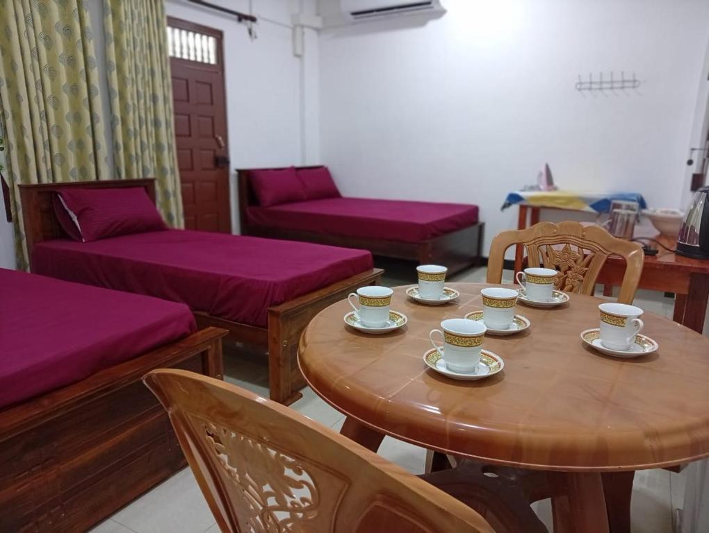 a room with a wooden table with cups and chairs at UK Villa & Guest house in Jaffna