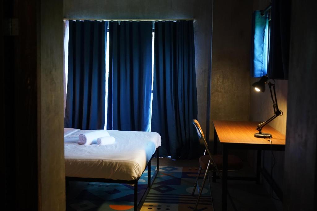 a bedroom with a bed and a desk and blue curtains at yolked suites in General Luna