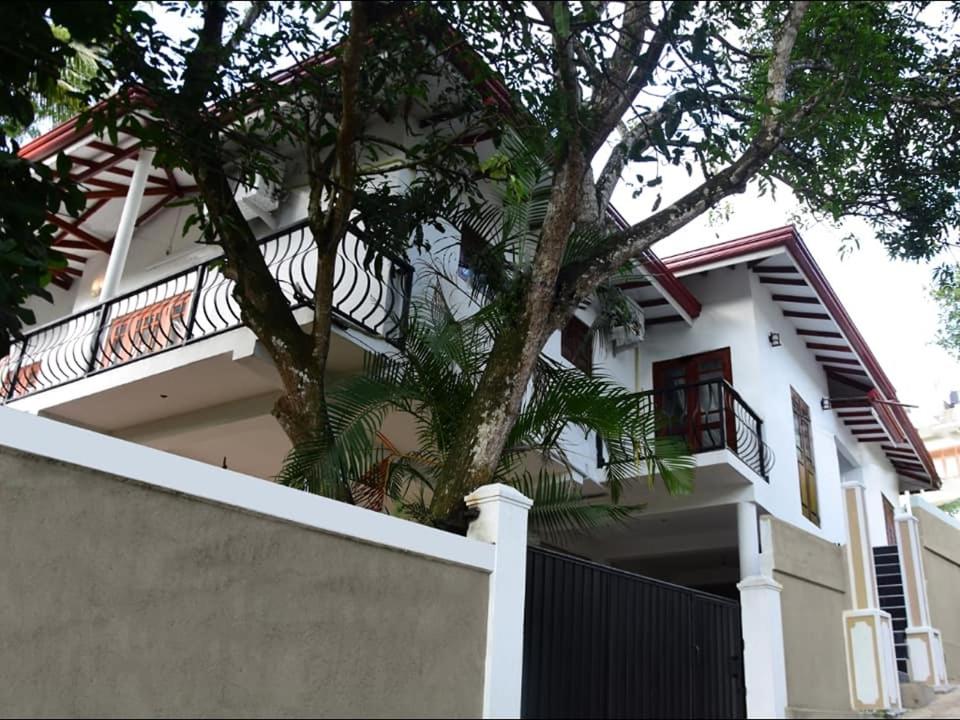 a white house with a fence and a tree at Ciel Grand Villa in Kandy