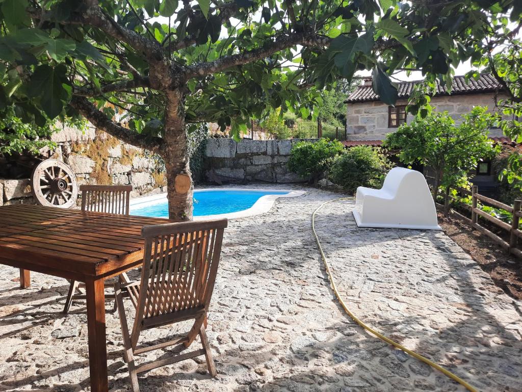 a table and chairs next to a tree and a pool at Dão country house in Silgueiros