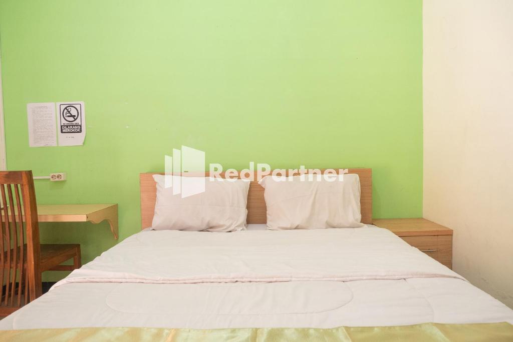 a bedroom with a bed with white sheets and a green wall at Wisma Handayani Syariah RedPartner near RSUD Wonosari in Yogyakarta