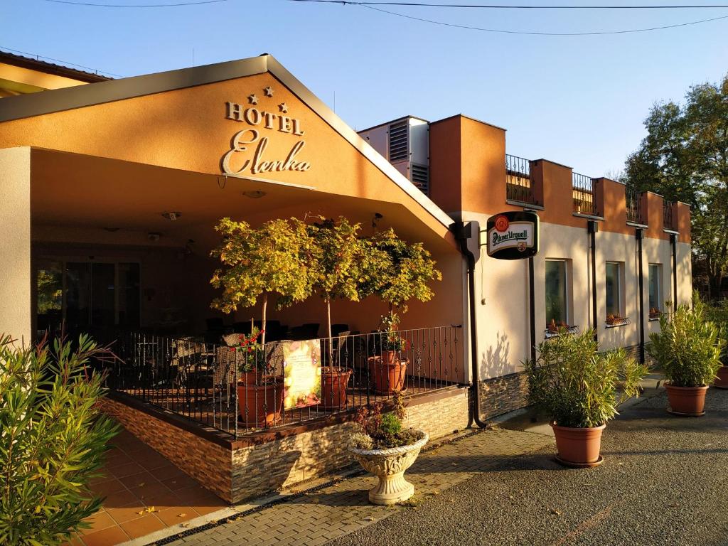 a hotel building with potted plants in front of it at Hotel Elenka in Veľký Meder