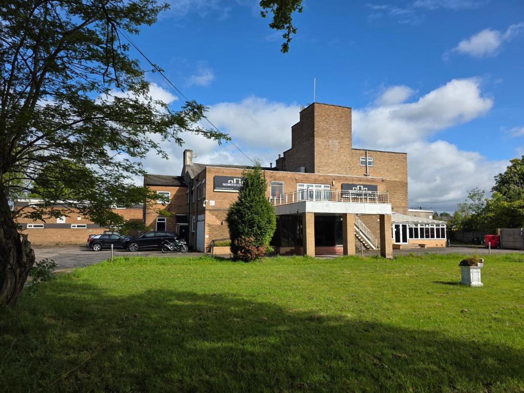 a large brick building with a grass field in front of it at The Paddington House in Warrington