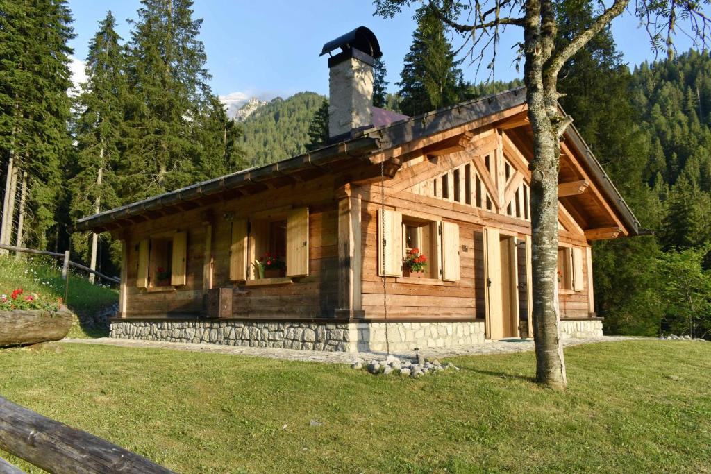 a log cabin in the woods with a tree at Chalet Brenta Dolomites in Madonna di Campiglio