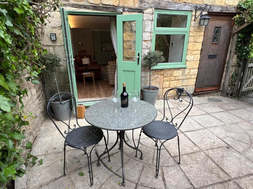 a table with two chairs and a bottle of wine at Wheelwright Cottage in Moreton in Marsh