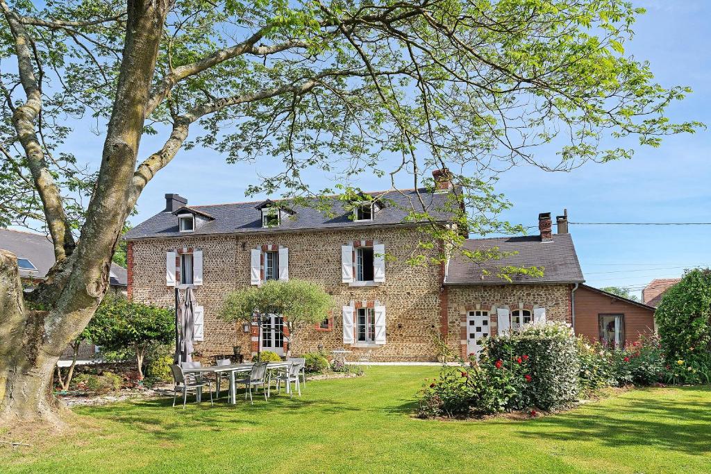 a brick house with tables and chairs in the yard at Chambres D'hotes Vignolo in Pontiacq-Viellepinte
