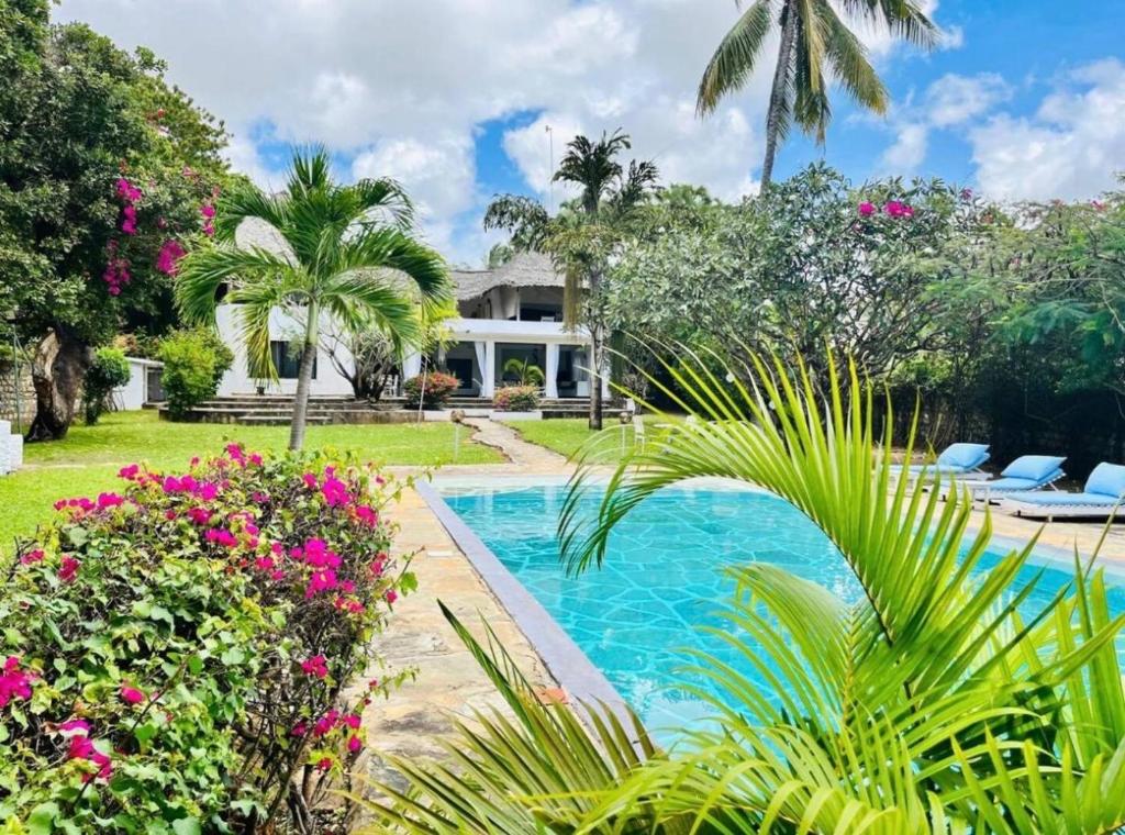 a swimming pool in front of a house with flowers at WHITE Nyumba Malindi - Boutique Villa in Malindi