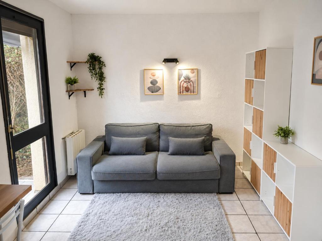 a living room with a couch and a window at Studio avec terrasse et jardin privatif - Figeac centre - Parking gratuit in Figeac