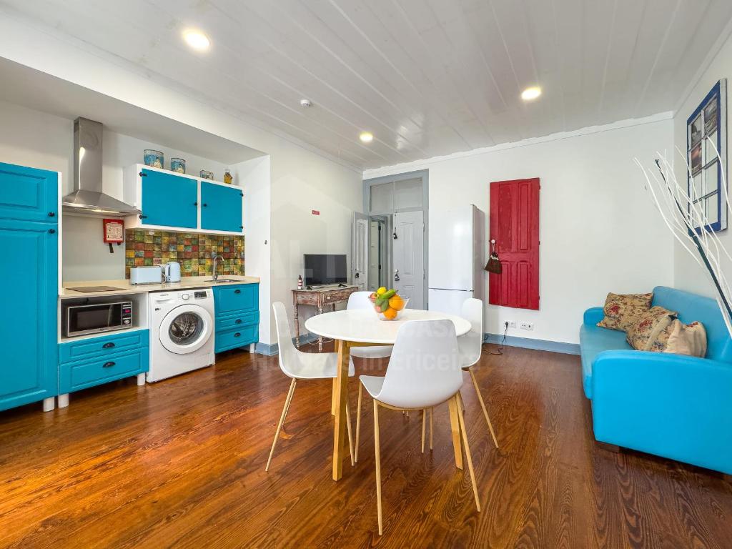a kitchen with blue cabinets and a table and chairs at Casas da villa - Apartments in Ericeira