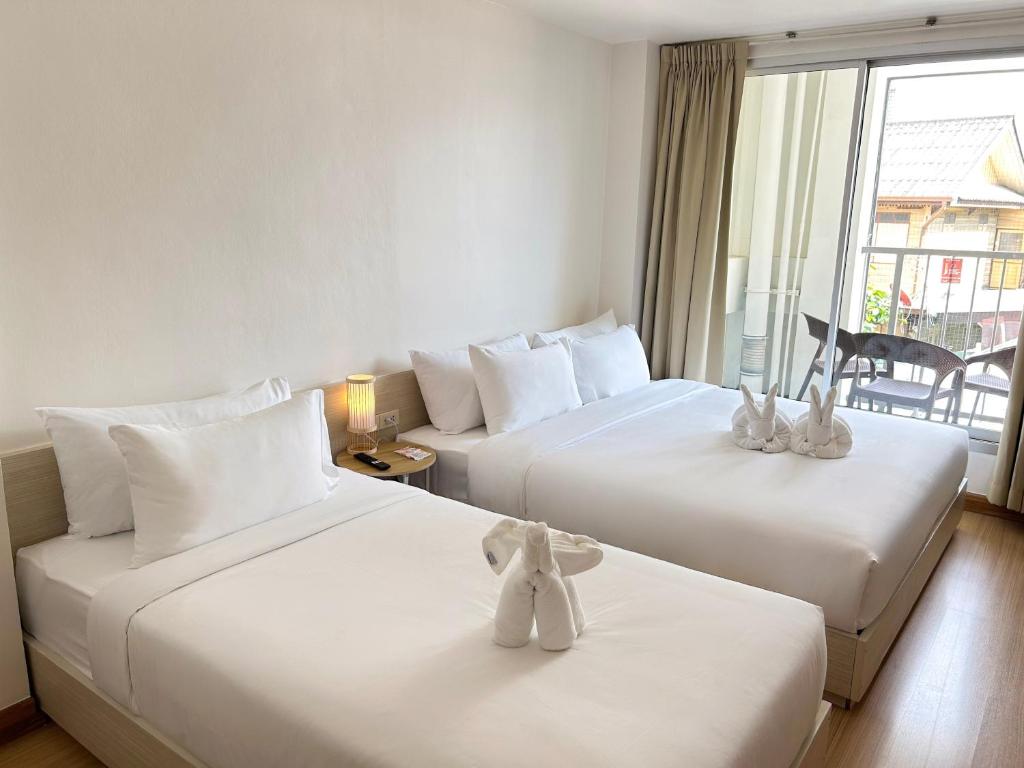 two beds in a hotel room with stuffed animals on them at Taradii Boutique in Bangkok