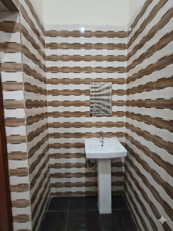 ein Badezimmer mit weißem Waschbecken und Holzwänden in der Unterkunft Hotel come inn in Palwal