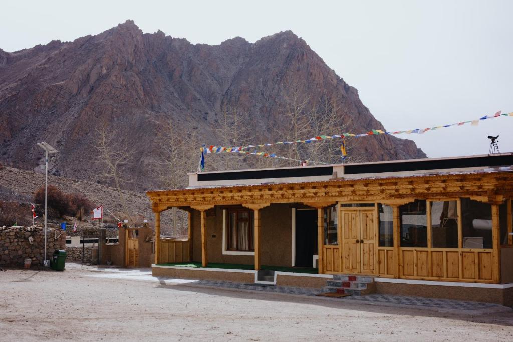 a small building with a mountain in the background at Shan at Uley in Leh