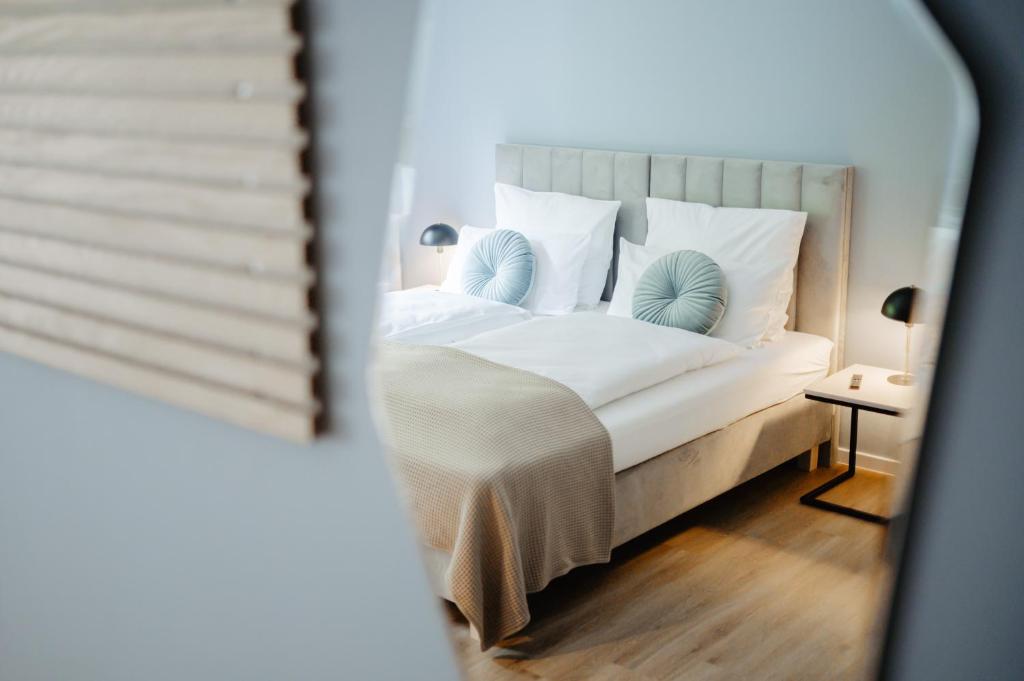 a bedroom with a bed with white sheets and blue pillows at HarzHold - Apartmenthotel in Osterode