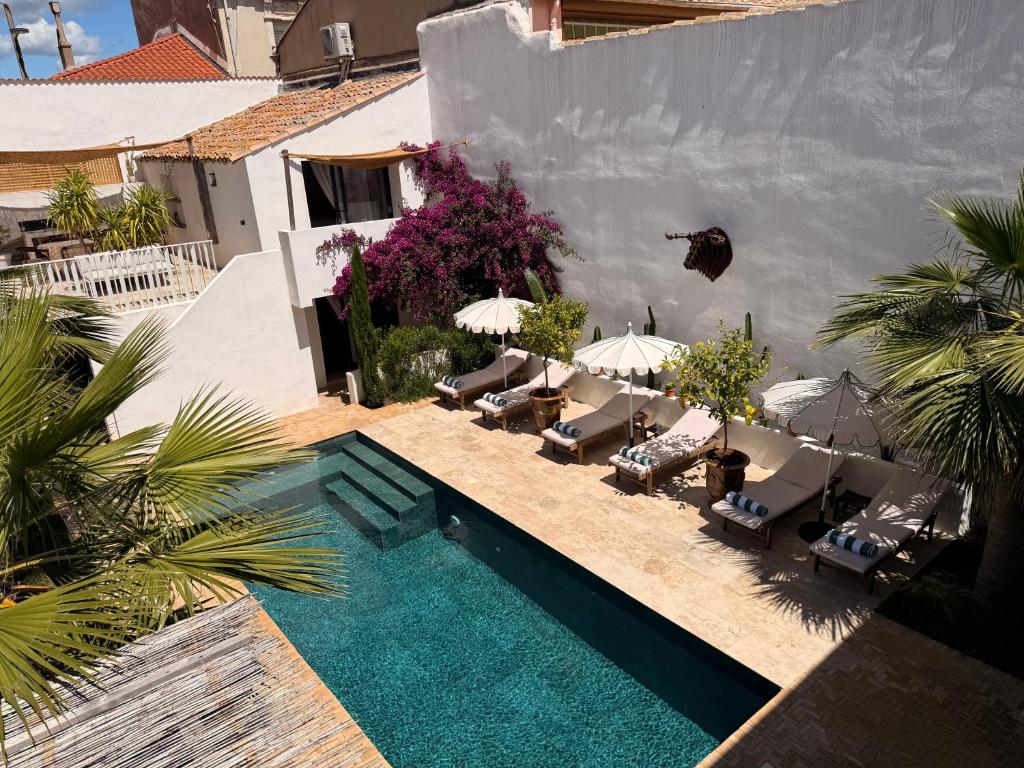 a swimming pool with chairs and umbrellas next to a building at La Maison De Ville - Piscine & SPA in Sète