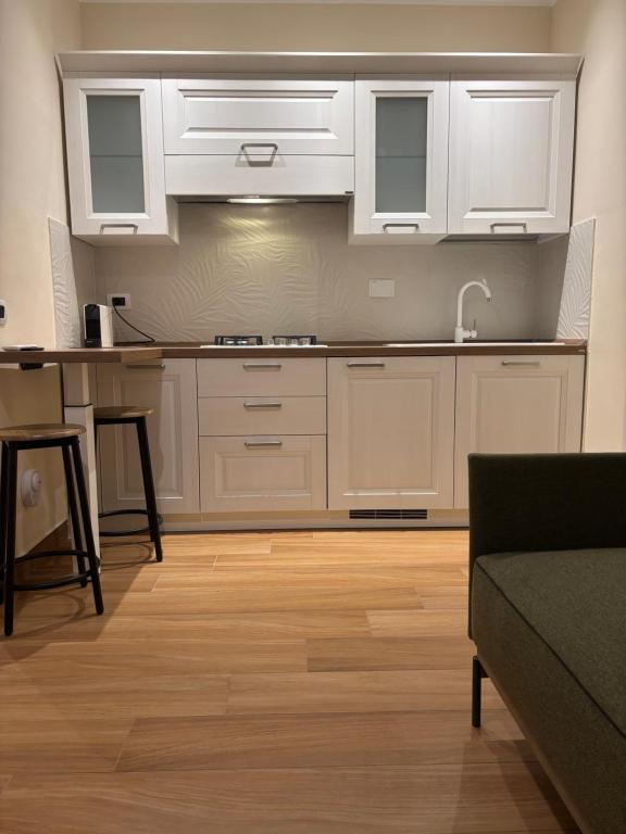 a kitchen with white cabinets and a wooden floor at Gioia apartment in Sabaudia