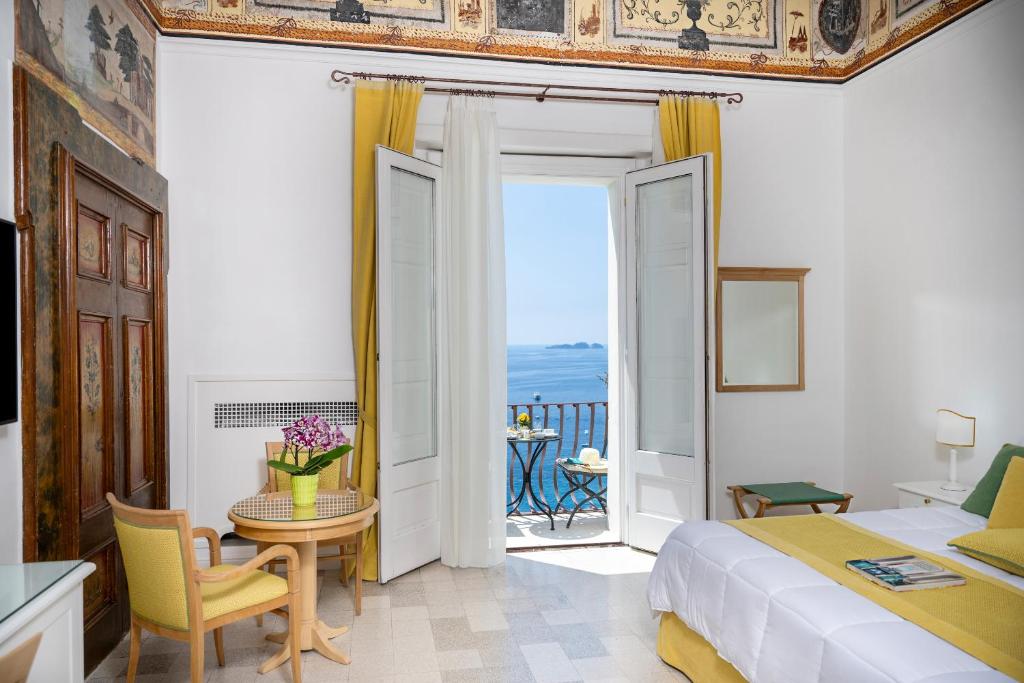 a bedroom with a bed and a table and a balcony at Albergo California in Positano