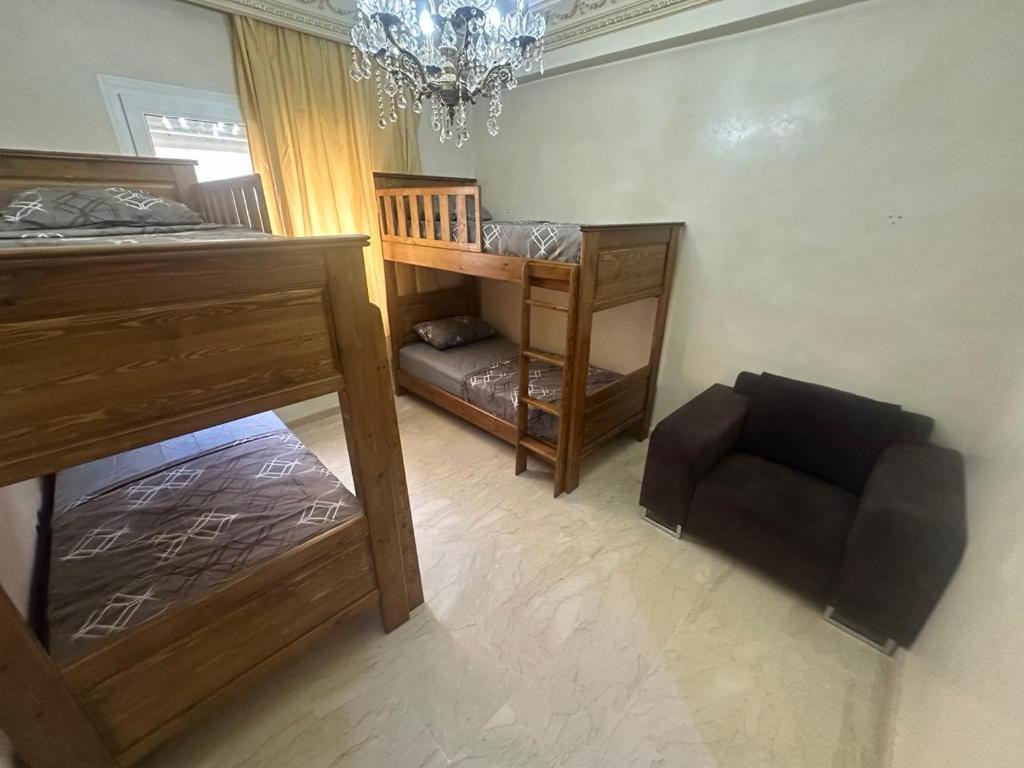a bedroom with bunk beds and a chair and a chandelier at Stars Hostel Tangier in Tangier