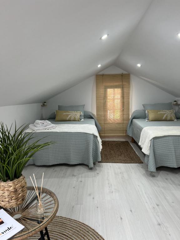 a attic room with two beds and a table at El Encanto de Sixto in Santa Marta de Ortigueira